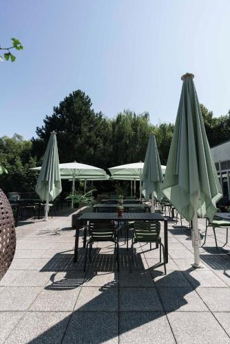 a group of tables and umbrellas on a patio at Seminaris Hotel Potsdam Griebnitzsee in Potsdam
