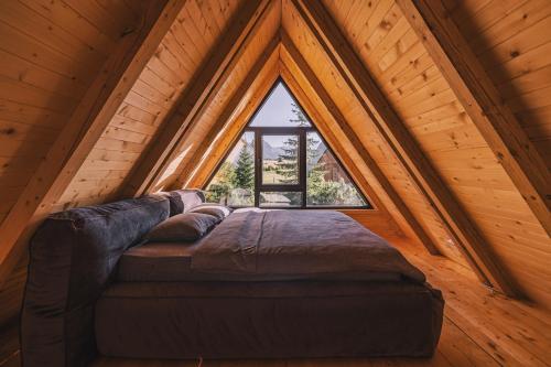 un grand lit dans une chambre avec une grande fenêtre dans l'établissement Mountain homes Durmitor 3, à Žabljak