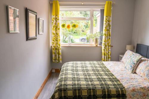 a bedroom with a bed and a window with yellow curtains at 6 Riverside Apart Sleeps 5 NEC 7mins BHX 8mins in Coleshill