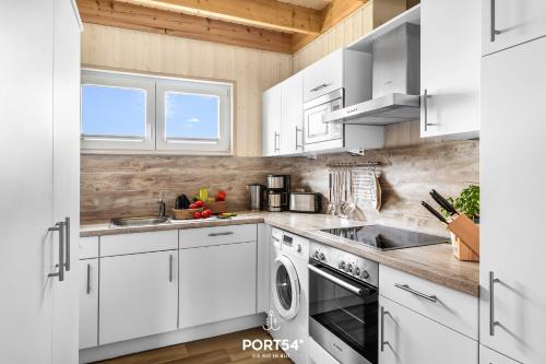 a kitchen with white cabinets and a dishwasher at Ferienhaus Lachmöwe Olpenitz in Olpenitz