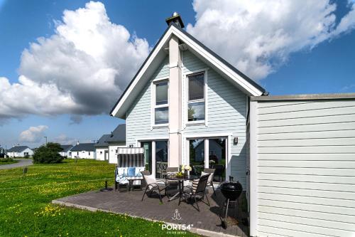 a white house with chairs and a table on a patio at Ferienhaus Strandglück Olpenitz in Olpenitz