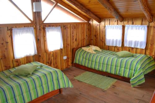 1 dormitorio con 2 camas en una cabaña de madera en Cabañas Natanael en Trevelín
