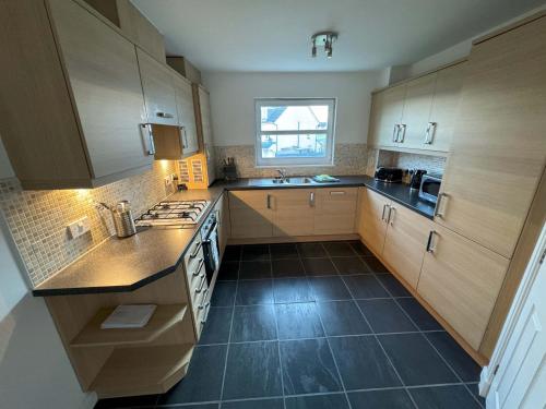 a kitchen with wooden cabinets and a black tile floor at Kingfisher Apartment in Dunfermline