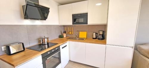 a kitchen with white cabinets and a sink and a microwave at Ferienwohnung Sol, Morro Jable, Meerblick, Klimaanlage, Pool in Morro del Jable