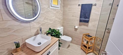 a bathroom with a sink and a mirror and a toilet at Ferienwohnung Sol, Morro Jable, Meerblick, Klimaanlage, Pool in Morro del Jable