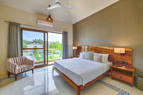 アンジュナにあるMelhor Stays Villa - L-M107 Luxury 4BHK villa with Private pool, Anjunaのベッドと椅子と窓のある寝室
