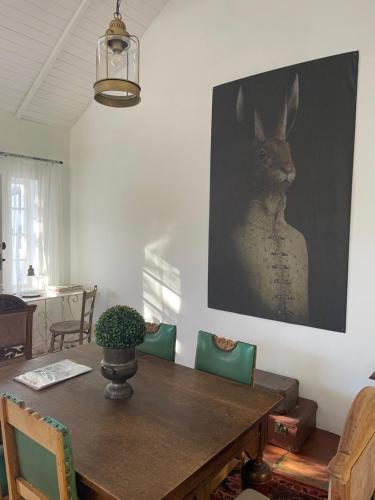a dining room table with a picture of a rabbit on the wall at 13 On Vigne in Greyton