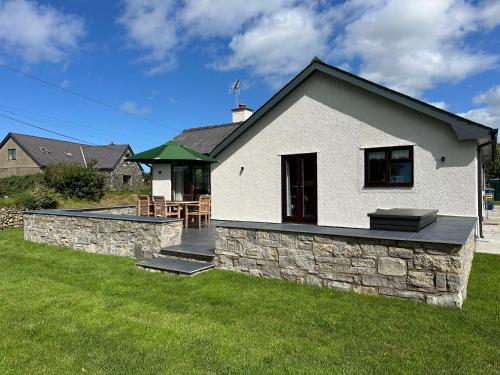 a white house with a stone wall in a yard at Encil Y Coed in Pwllheli