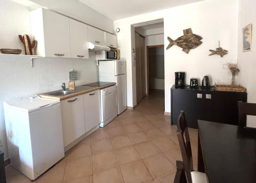 une cuisine avec des armoires blanches et un réfrigérateur blanc dans l'établissement SAINT FLORENT - T3 Climatisé piscine FLO147, à Saint-Florent
