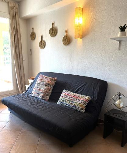 - un canapé noir dans le salon avec deux oreillers dans l'établissement SAINT FLORENT - T3 Climatisé piscine FLO147, à Saint-Florent