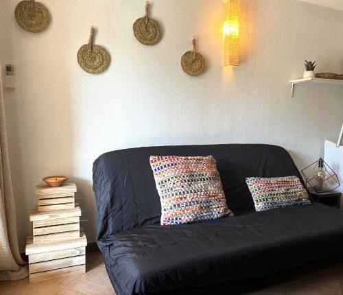 - un canapé noir dans le salon avec deux oreillers dans l'établissement SAINT FLORENT - T3 Climatisé piscine FLO147, à Saint-Florent