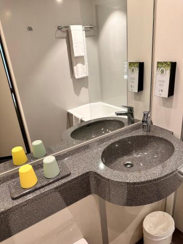 a bathroom with a sink and a mirror at Hôtel Kyriad Rennes Centre Gare in Rennes