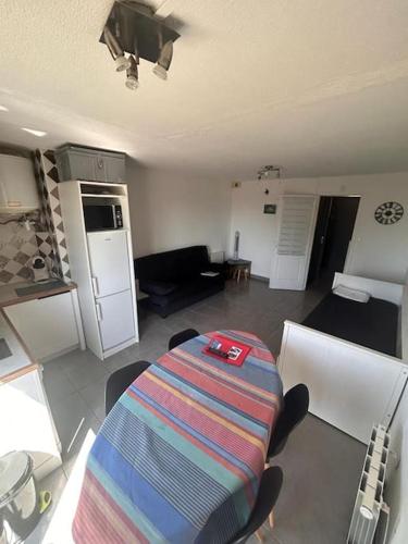 un salon avec une table et une cuisine dans l'établissement Cap Agde Studio-Cabine -Vue Jardin, au Cap d'Agde