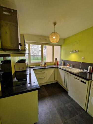 une cuisine avec des murs jaunes et un comptoir noir dans l'établissement Le Square - Tramway - Centre - 4p - Rêve au Mans, au Mans