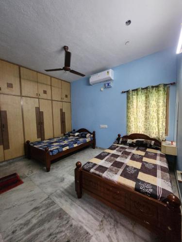 a bedroom with two beds and a ceiling fan at Holiday Home Madurai Bharathi Nagar - FF in Tallākulam