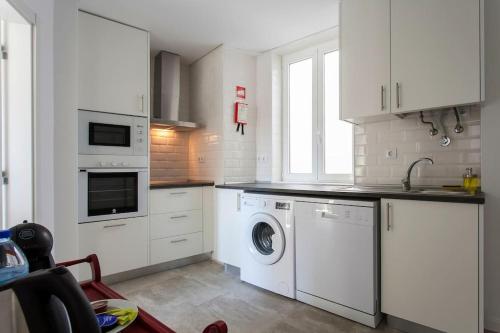 a kitchen with white cabinets and a washing machine at Near the River 3 Bedrooms Flat, with AC for 9 in Lisbon
