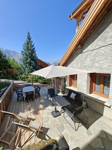 a patio with a table and chairs and an umbrella at "La bâtisse des prés" in Puy-Saint-Vincent