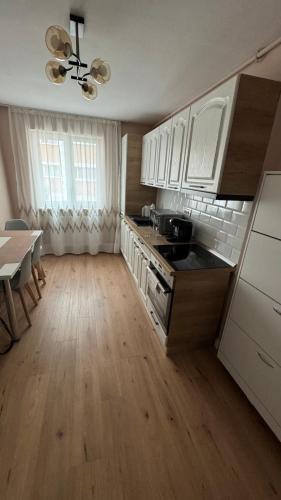 a kitchen with white cabinets and a wooden floor at Citadelle Apart in Alba Iulia