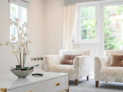 a living room with two chairs and a vase of flowers on a table at Pass The Keys Stunning 5 Bedroom Spacious Home in Bookham