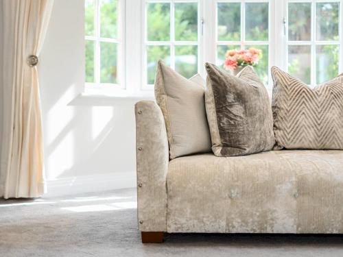 a couch with pillows in a living room with a window at Pass The Keys Stunning 5 Bedroom Spacious Home in Bookham
