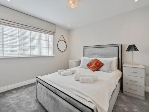 a white bedroom with a large bed and a window at Pass The Keys Stunning 5 Bedroom Spacious Home in Bookham