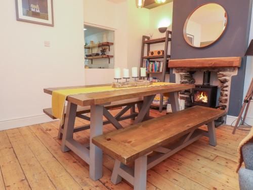 a dining room with a table and a fireplace at Heol Madog in Porthmadog
