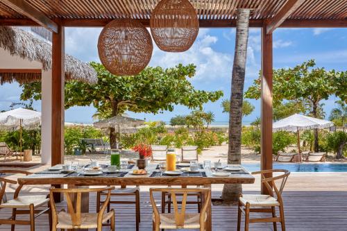 a table and chairs on a deck with a view of the ocean at Villa Praia - La Villa Group in Jericoacoara