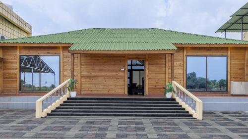 a small wooden building with stairs and a green roof at The Arowana Divine in Nānded