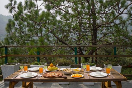 a wooden table with food and drinks on it at Alaya Stays Duplex Cottage with Tree House - Suro Woodcrest Chalet in Shogi