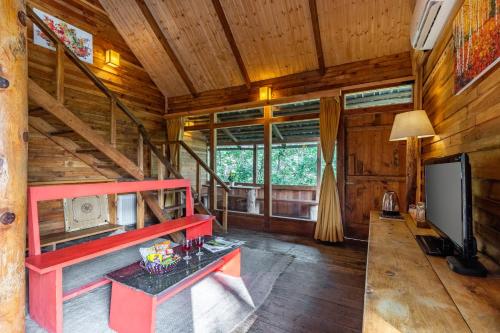a living room with a red bench in a cabin at Alaya Stays Duplex Cottage with Tree House - Suro Woodcrest Chalet in Shogi