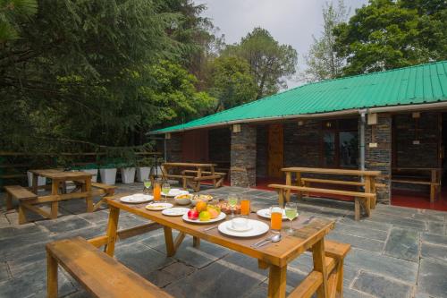 a picnic table with plates of food on a patio at Alaya Stays Cottage with Tree House - Suro Woodbine Chalet in Shogi