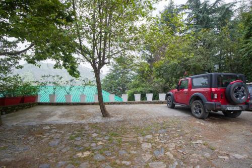 a red jeep parked next to a tree at Alaya Stays Cottage with Tree House - Suro Woodbine Chalet in Shogi