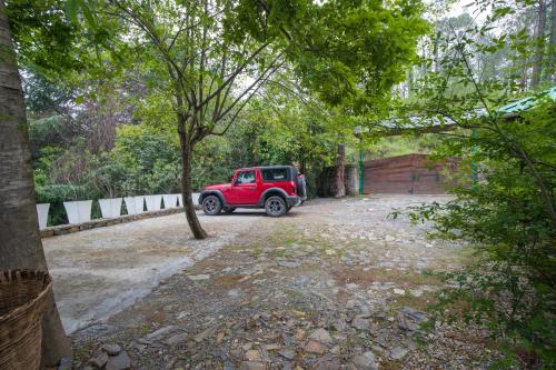 a red jeep parked on a dirt road at Alaya Stays Cottage with Tree House - Suro Woodbine Chalet in Shogi