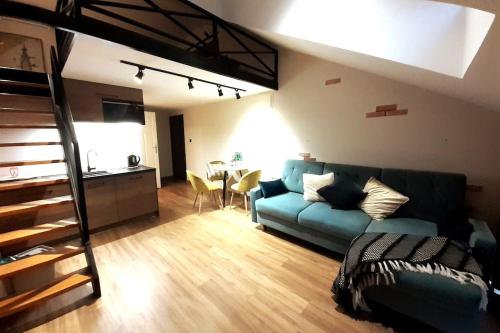 Una sala de estar con un sofá azul y una cocina. en Loft Apartment Old Town - G47, en Cracovia