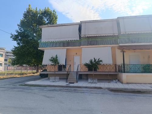 a building with a porch with two potted plants on it at Panos House - Warm and cozy retreat in Tríkala