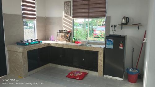 a kitchen with a black refrigerator and a window at Andalus Cottage in Wakaf Baharu