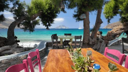 a table and chairs on a beach with the ocean at Lakki Village in Aegiali