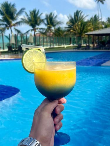 a hand holding a drink with a lemon slice at Brisas de Tabatinga Flat in Conde