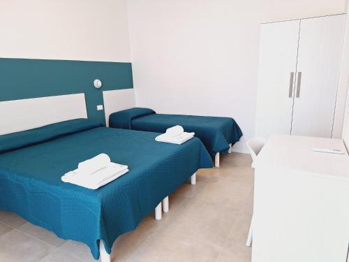 a room with three beds with blue sheets and a table at Re Lear Expo in Verona