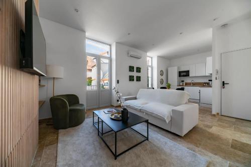 a living room with a white couch and a table at Résidence Jaures - Appartements design et climatisés en centre ville in Vichy