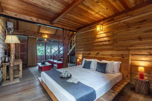 a bedroom with a bed in a wooden room at Alaya Stays Duplex Cottage with Tree House - Suro Woodcrest Chalet in Shogi