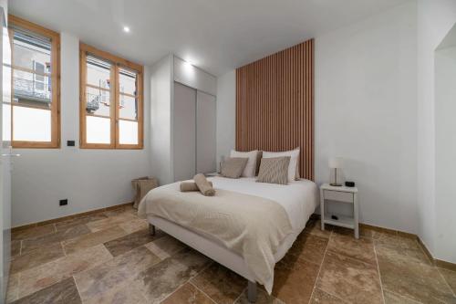 a white bedroom with a large bed and two windows at Résidence Jaures - Appartements design et climatisés en centre ville in Vichy