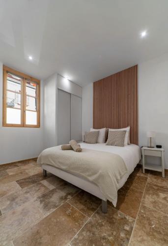 a white bedroom with a large bed and a window at Résidence Jaures - Appartements design et climatisés en centre ville in Vichy
