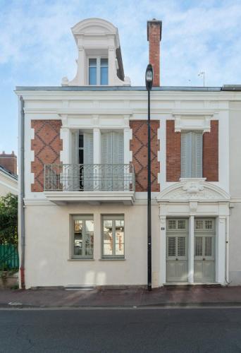 a white building with a balcony on top of it at Résidence Jaures - Appartements design et climatisés en centre ville in Vichy
