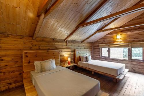 a bedroom with two beds in a log cabin at Alaya Stays Duplex Cottage with Tree House - Suro Woodcrest Chalet in Shogi