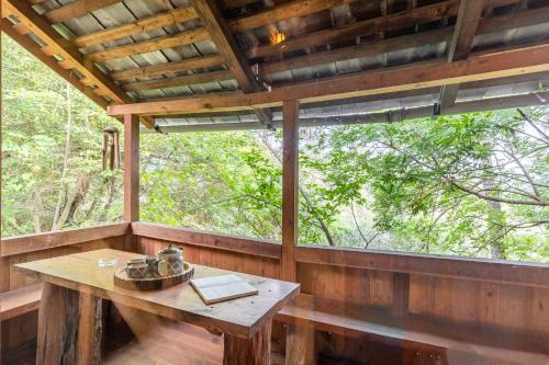 a tree house with a table in the porch at Alaya Stays Duplex Cottage with Tree House - Suro Woodcrest Chalet in Shogi