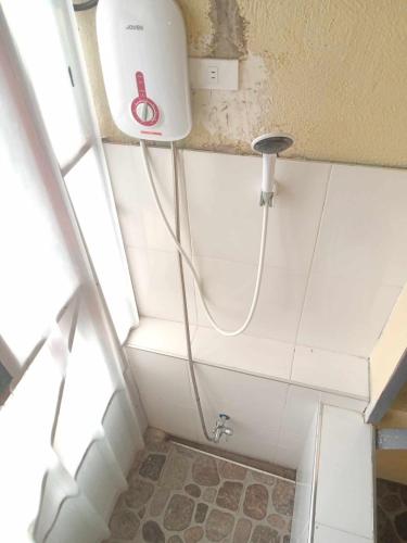 a shower in a bathroom with a hose attached to the wall at DaLei Suites in Pamplona in Tambojangin