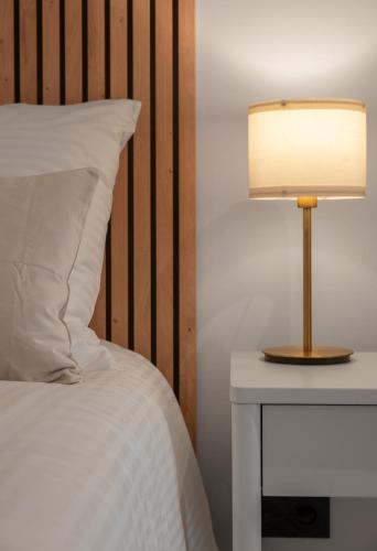a bed with a lamp on a nightstand next to a white bed at Résidence Jaures - Appartements design et climatisés en centre ville in Vichy