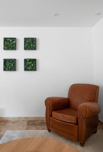 a brown chair in a room with paintings on the wall at Résidence Jaures - Appartements design et climatisés en centre ville in Vichy