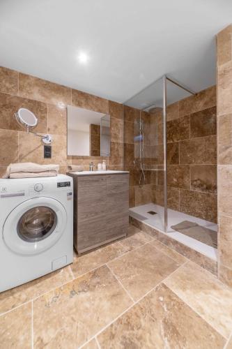 a bathroom with a washing machine and a shower at Résidence Jaures - Appartements design et climatisés en centre ville in Vichy